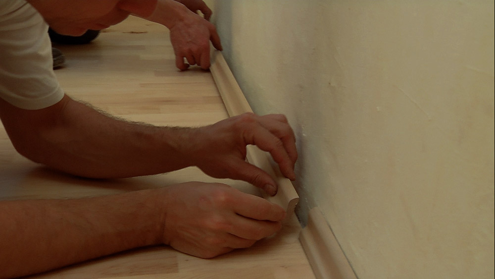 Fussleisten werden an der Wand angebracht.